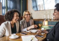 Three women laughing and chatting at a café.