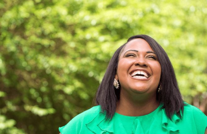 Smiling woman enjoying a sunny outdoor moment.